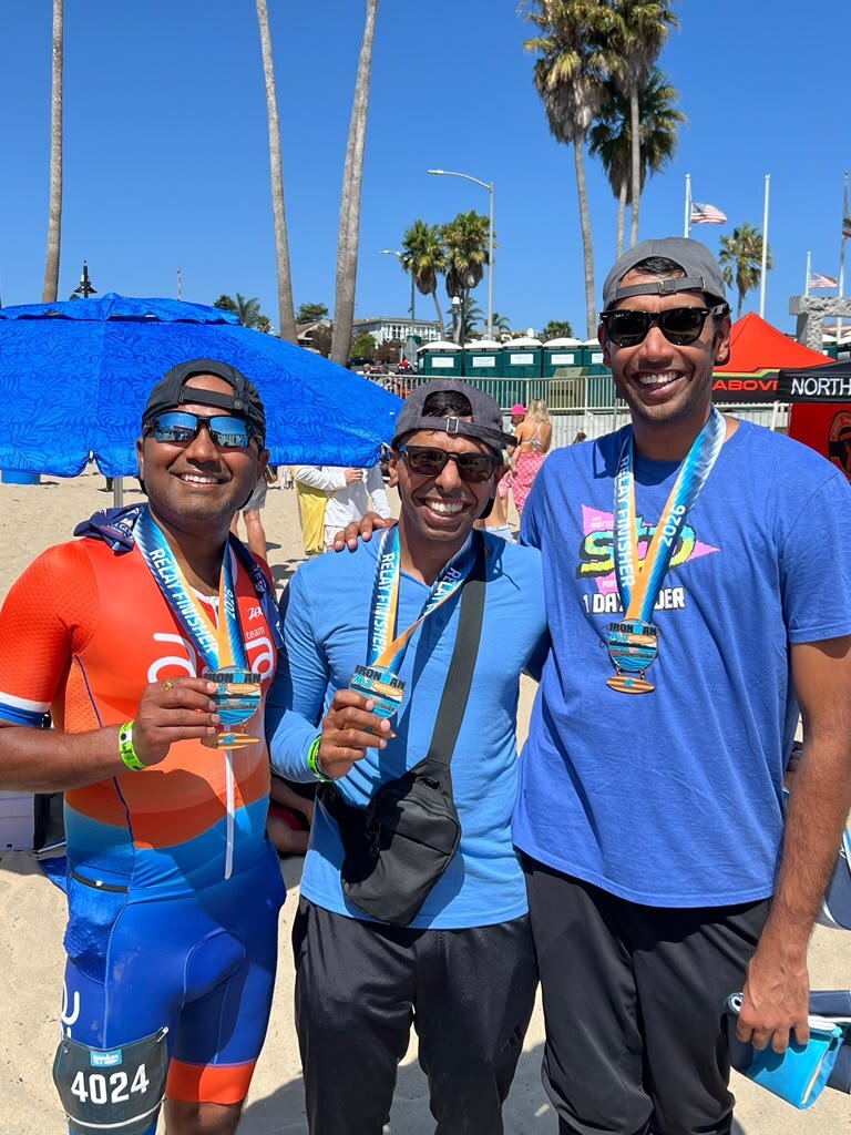 Three relay finishers displaying their IRONMAN 70.3 medals